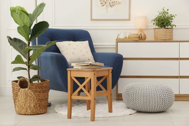 Photo of Stool, books, armchair and houseplants in room. Interior design