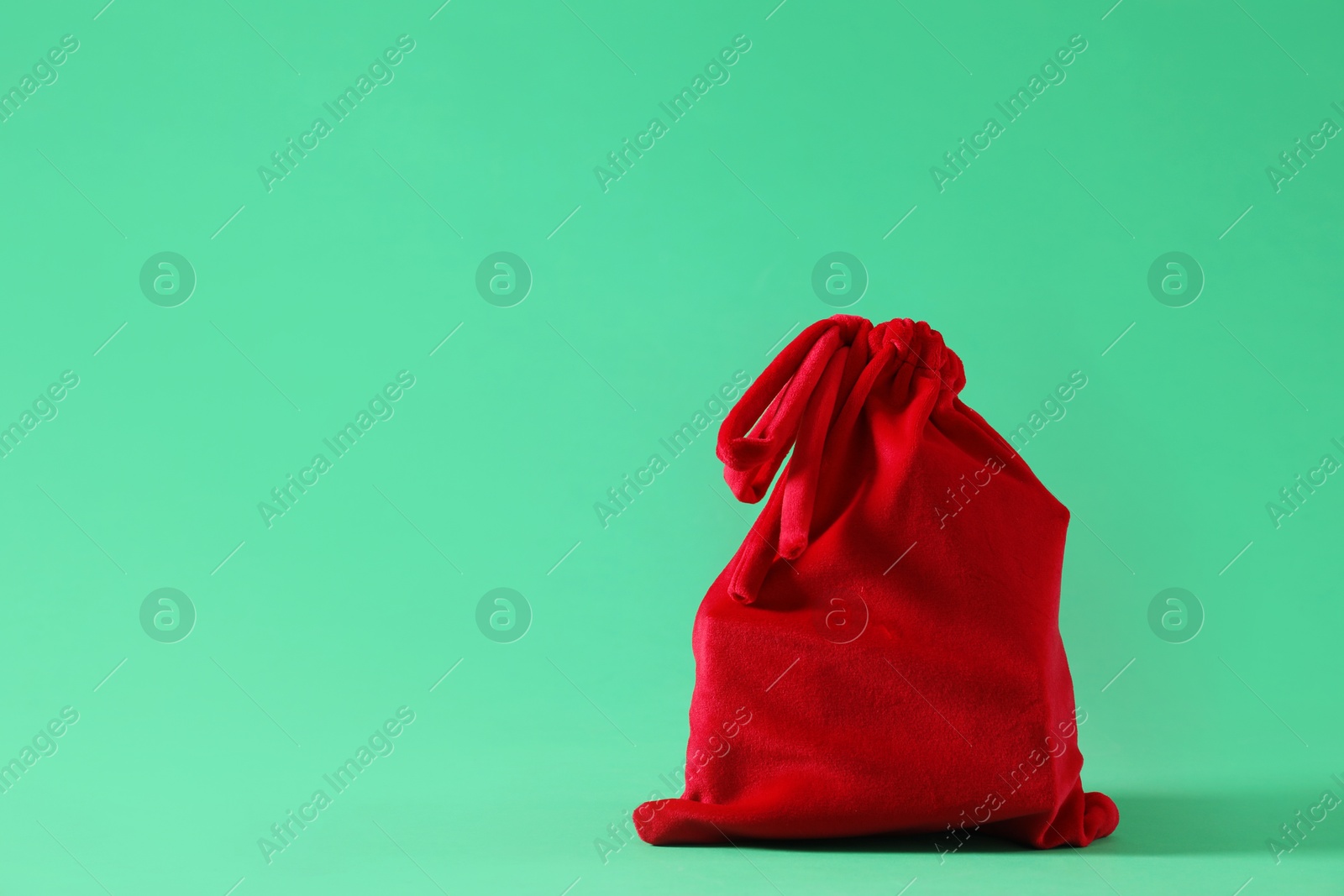 Photo of Red Santa Claus bag on green background, space for text