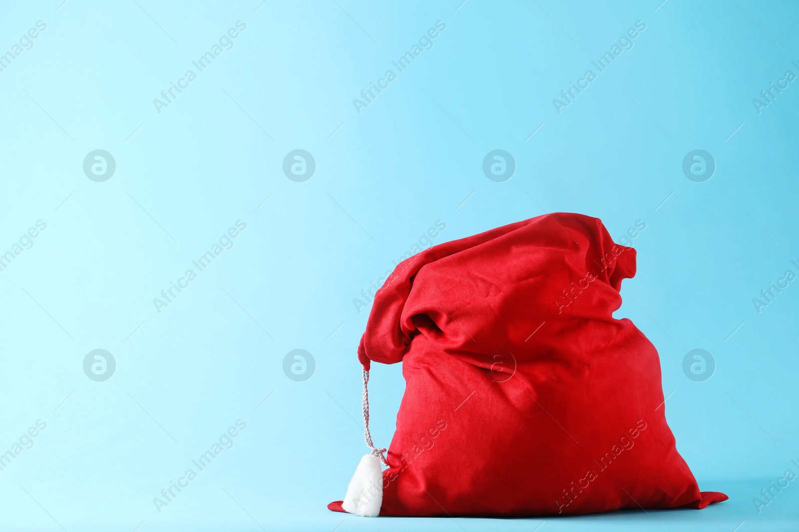 Photo of Red Santa Claus bag on light blue background, space for text