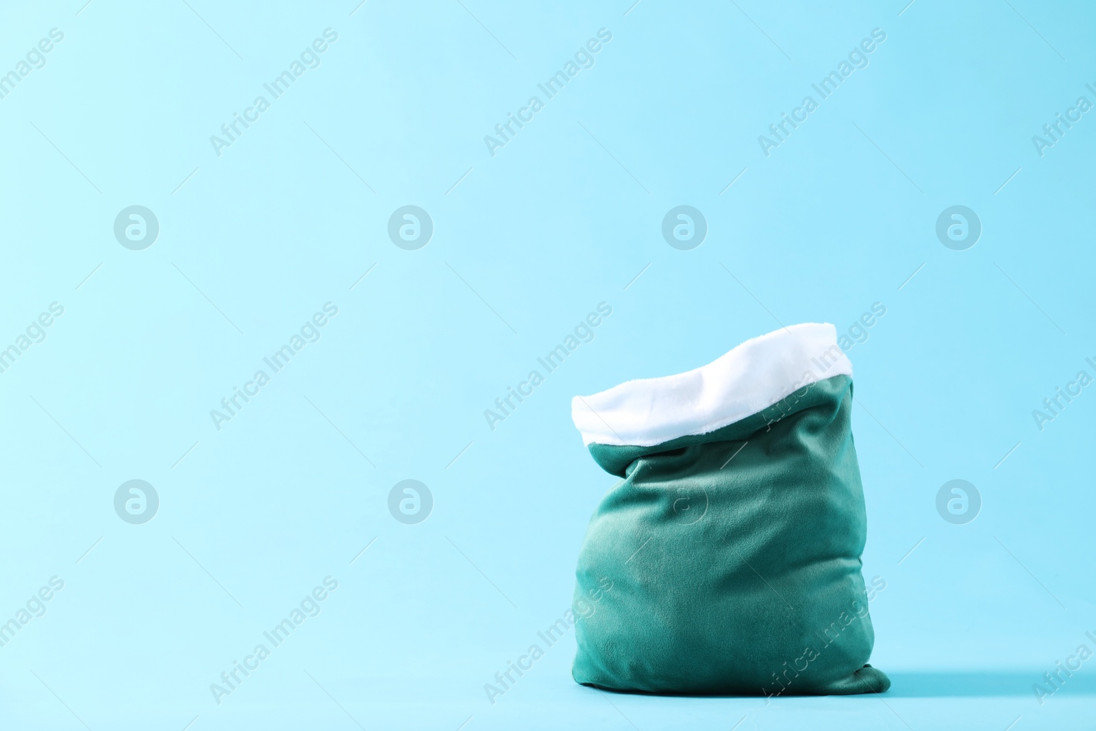 Photo of Green Santa Claus bag on light blue background, space for text