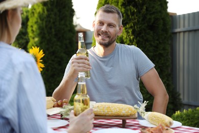 Photo of Friends with drinks enjoying picnic at table in garden