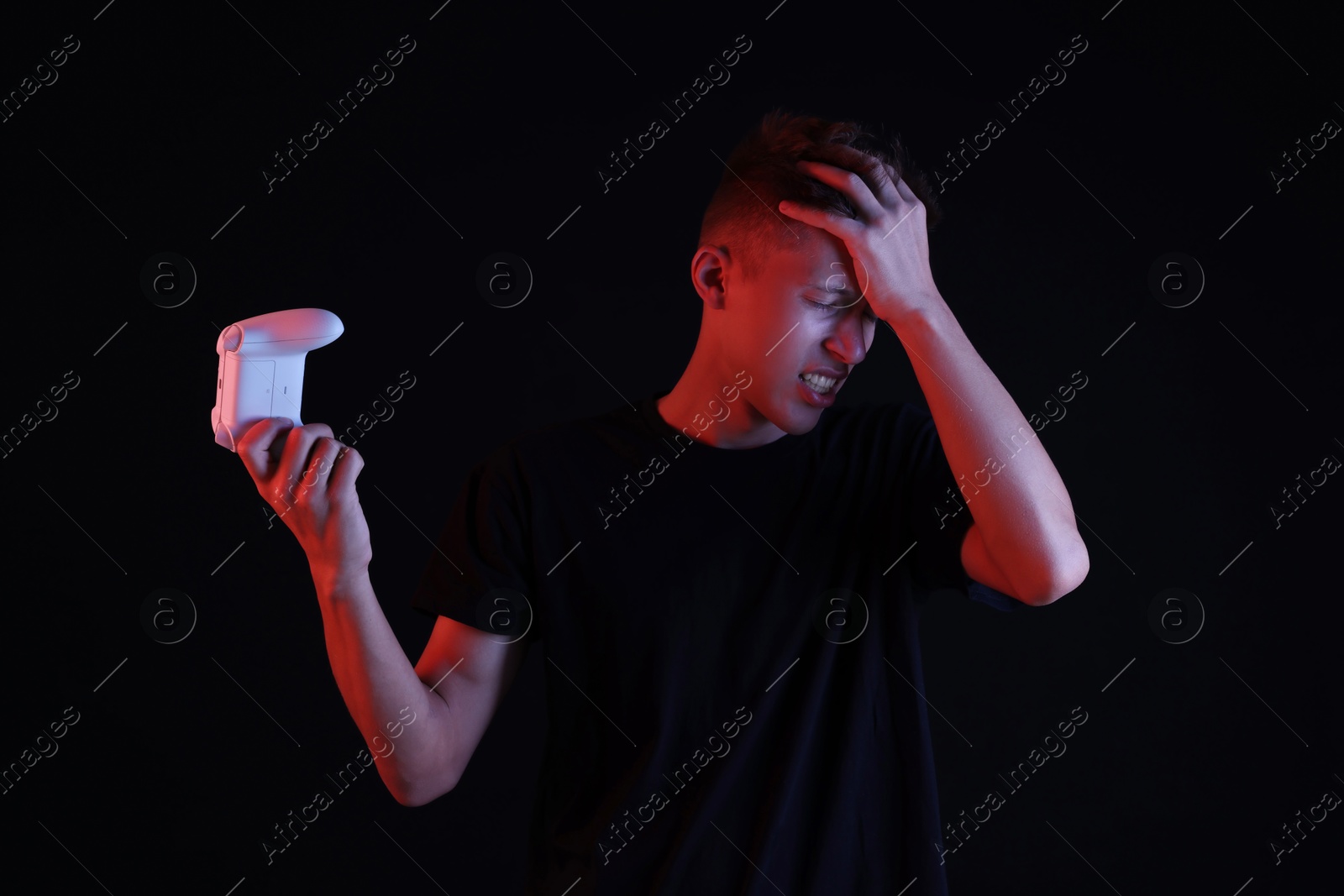 Photo of Unhappy young man with controller on black background