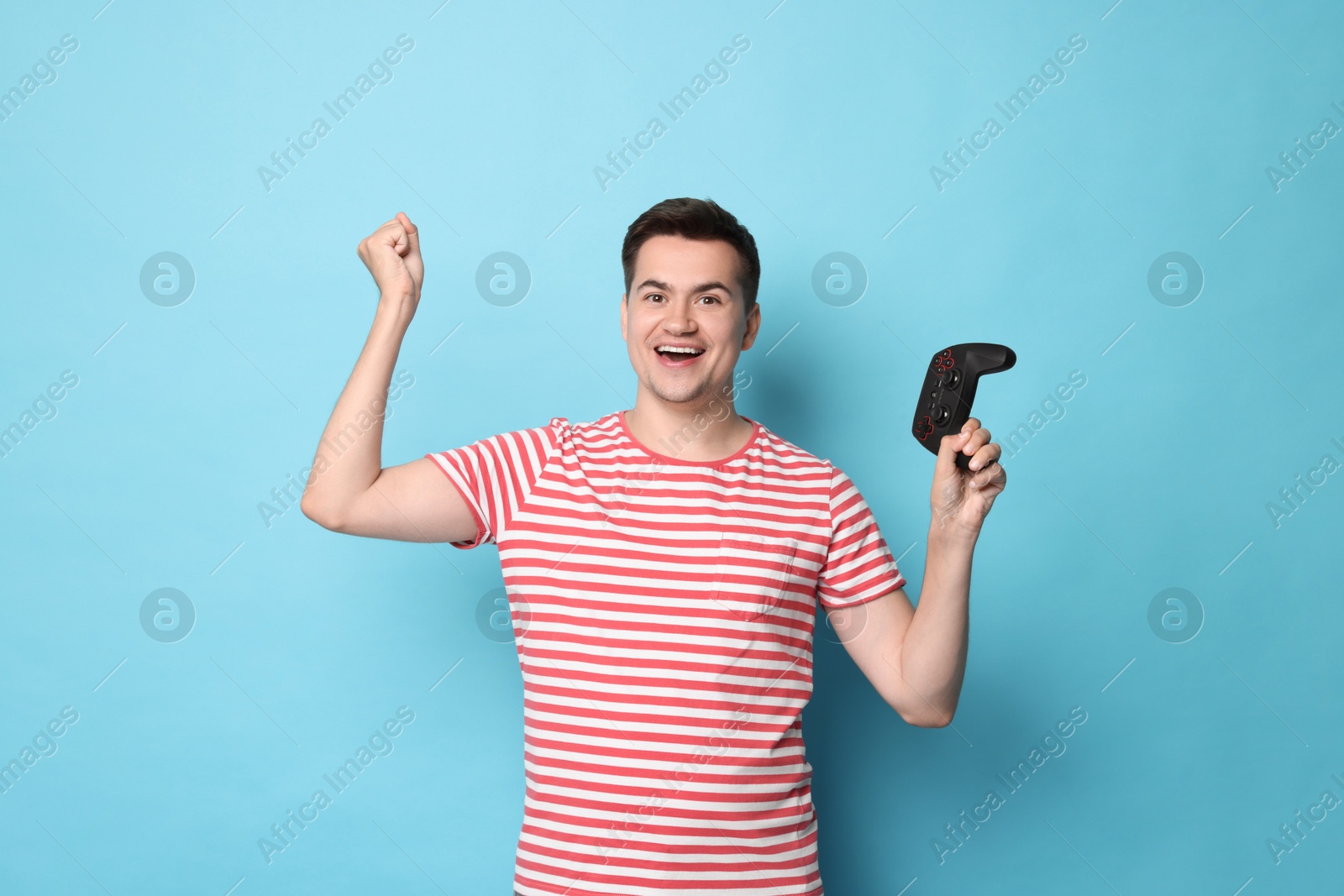 Photo of Happy young man with controller on light blue background