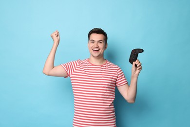 Photo of Happy young man with controller on light blue background