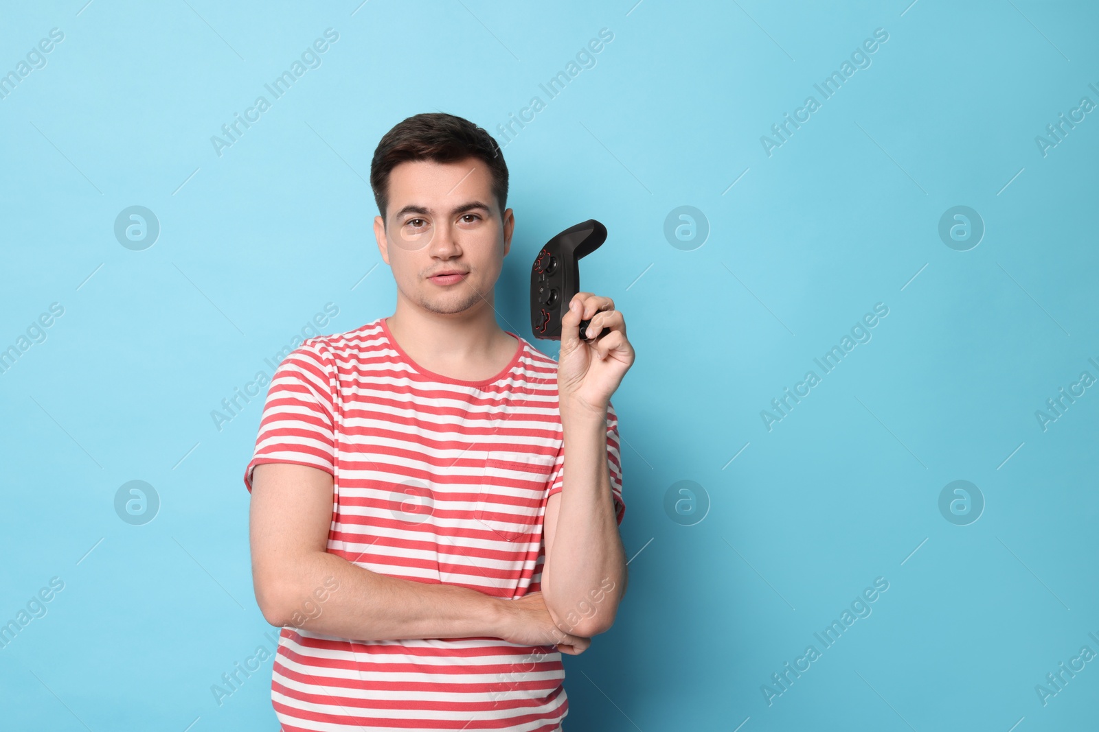 Photo of Young man with controller on light blue background