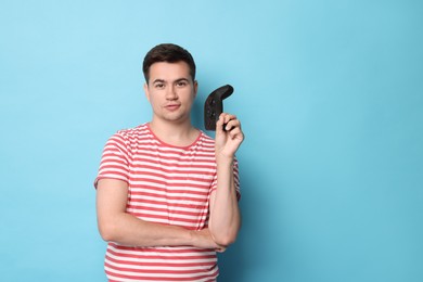 Young man with controller on light blue background