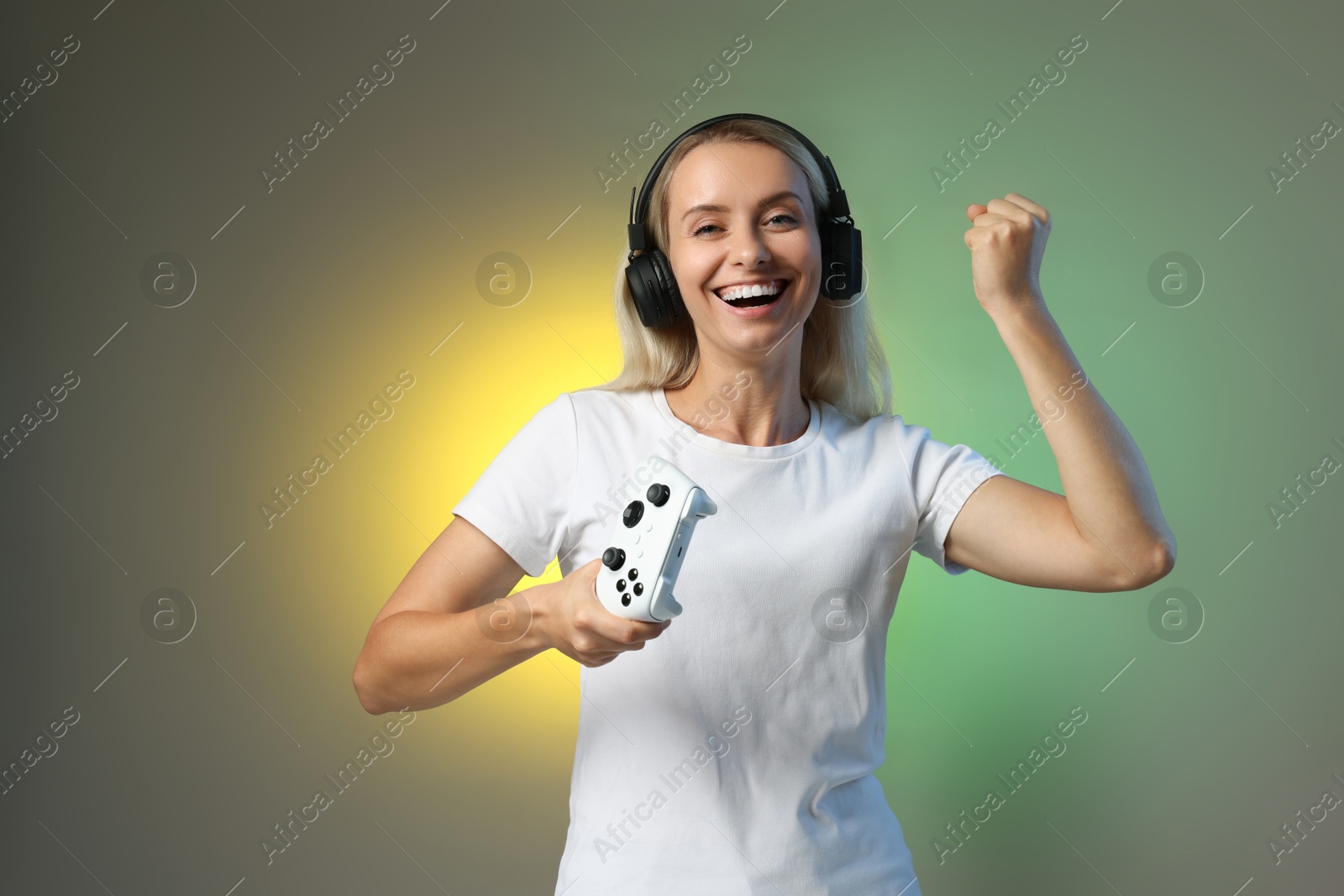 Photo of Happy woman in headphones with controller on color background