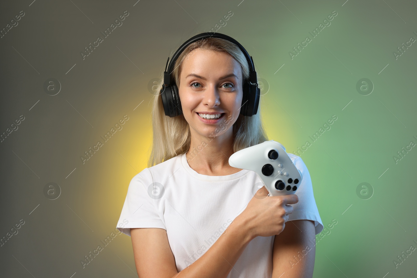 Photo of Happy woman in headphones with controller on color background