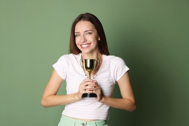 Photo of Happy winner with gold trophy cup on green background