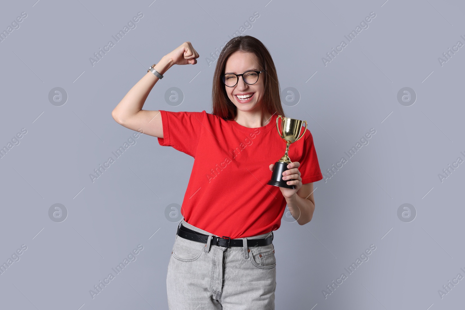 Photo of Happy winner with gold trophy cup on gray background