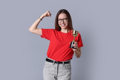 Photo of Happy winner with gold trophy cup on gray background