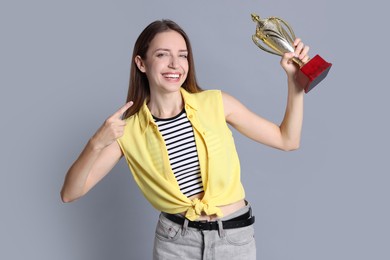 Photo of Happy winner with gold trophy cup on gray background