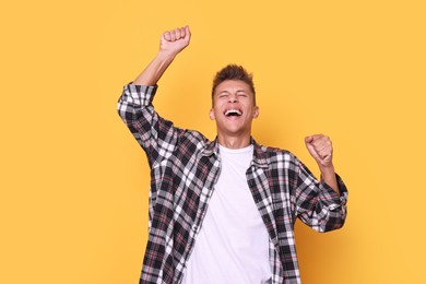 Happy young student in checkered shirt on yellow background