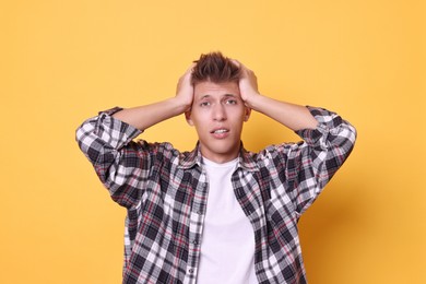 Young student having stress before exam on yellow background