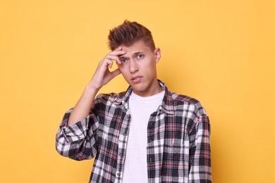 Young student having stress before exam on yellow background