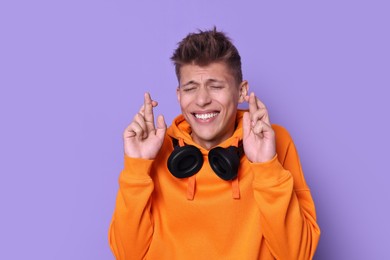 Photo of Excited young student crossing fingers on violet background. Hope for good exam result