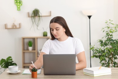 Student studying with laptop at wooden table indoors