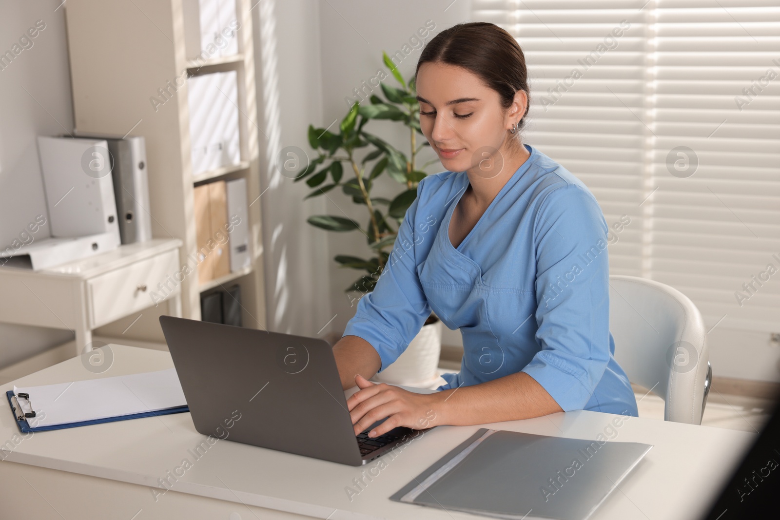 Photo of Medical student studying with laptop at table indoors