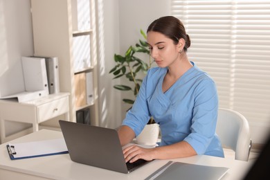 Photo of Medical student studying with laptop at table indoors