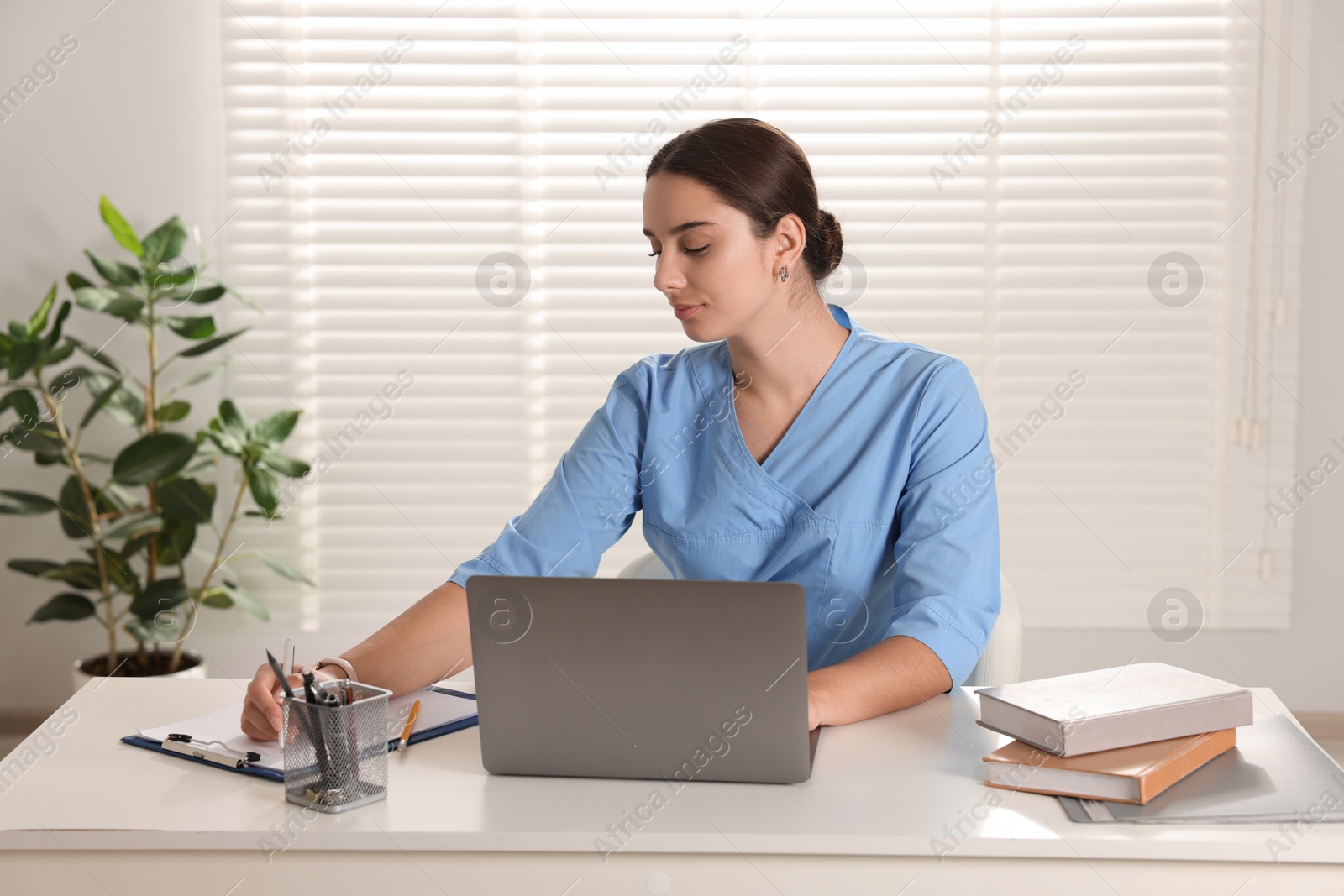 Photo of Medical student studying with laptop at table indoors