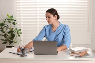 Photo of Medical student studying with laptop at table indoors