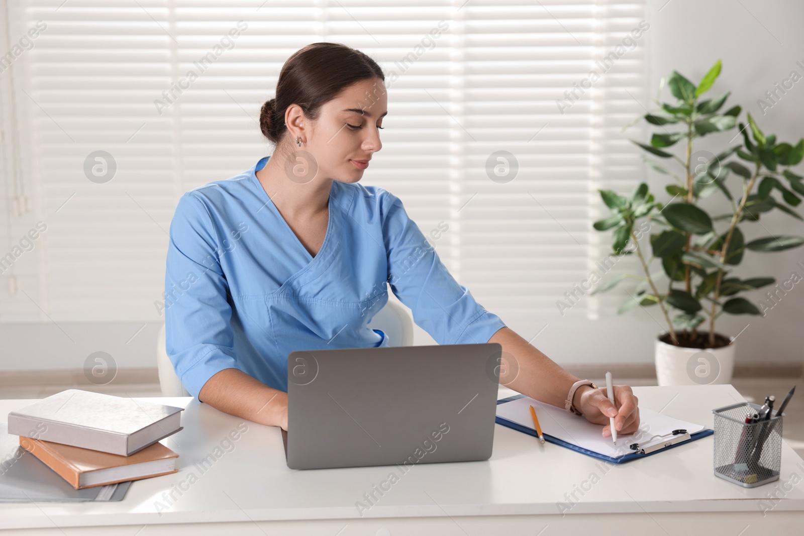 Photo of Medical student studying with laptop at table indoors