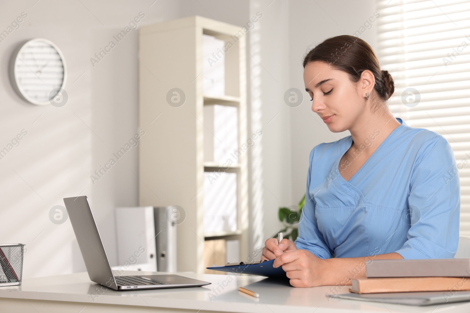 Photo of Medical student taking notes while studying at table indoors