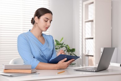 Photo of Medical student taking notes while studying at table indoors