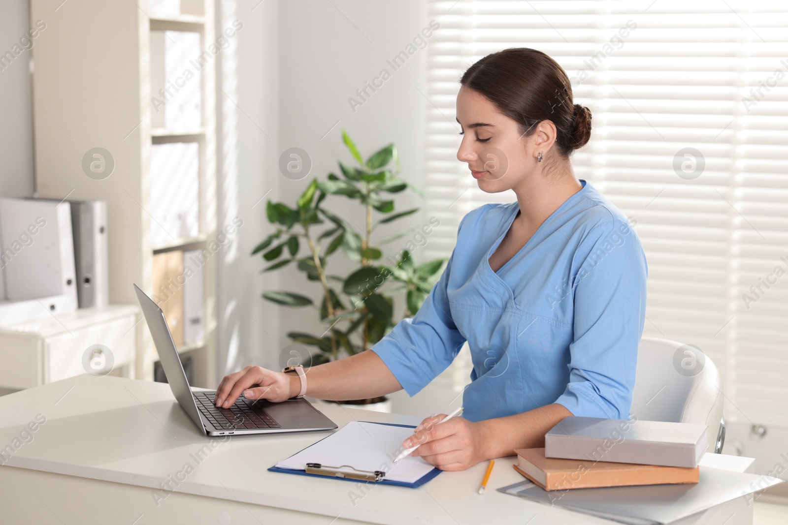 Photo of Medical student studying with laptop at table indoors