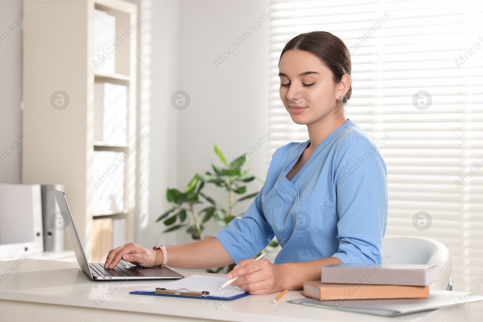 Photo of Medical student studying with laptop at table indoors