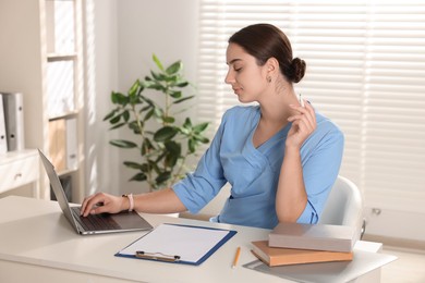 Medical student studying with laptop at table indoors