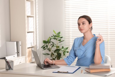 Medical student studying with laptop at table indoors