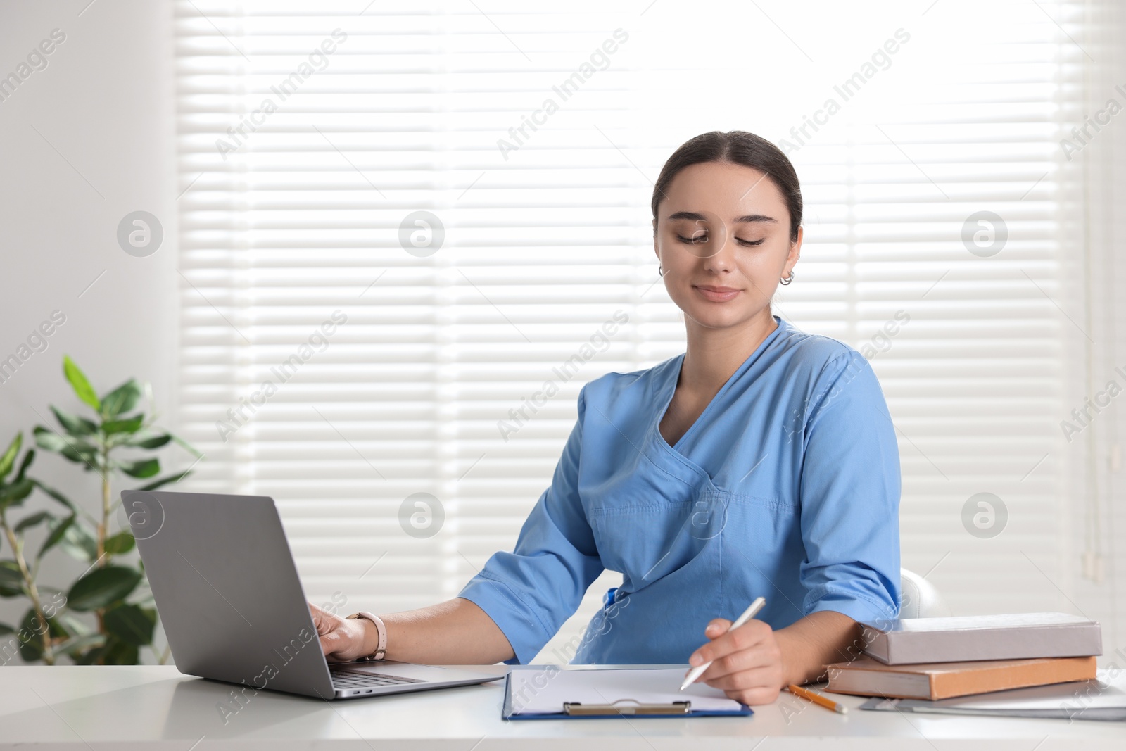 Photo of Medical student studying with laptop at table indoors