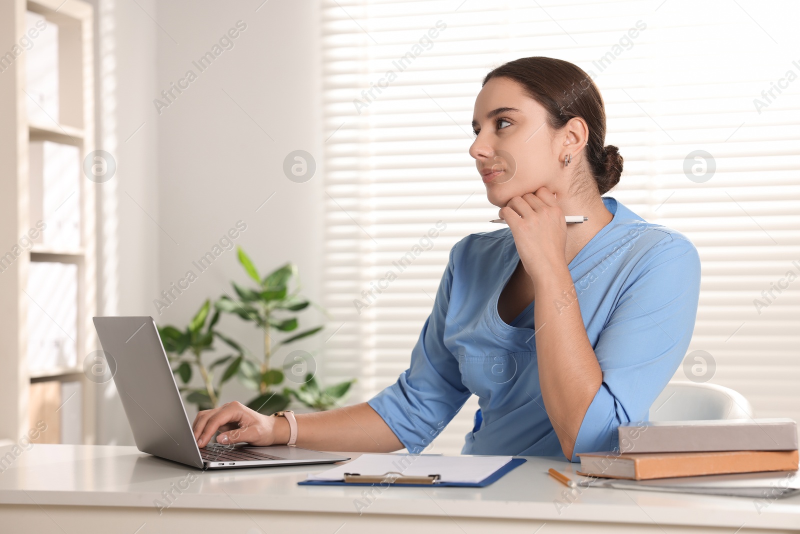 Photo of Medical student studying with laptop at table indoors