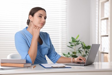 Medical student studying with laptop at table indoors