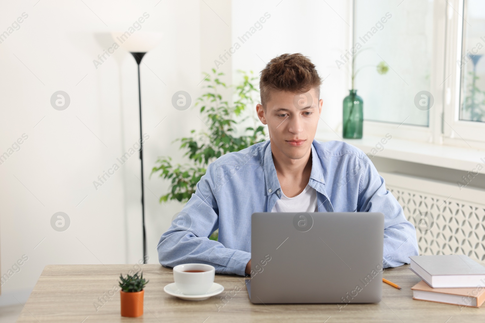 Photo of Student studying with laptop at wooden table indoors