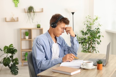 Student in headphones studying at wooden table indoors