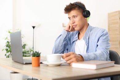 Photo of Student in headphones studying at table indoors