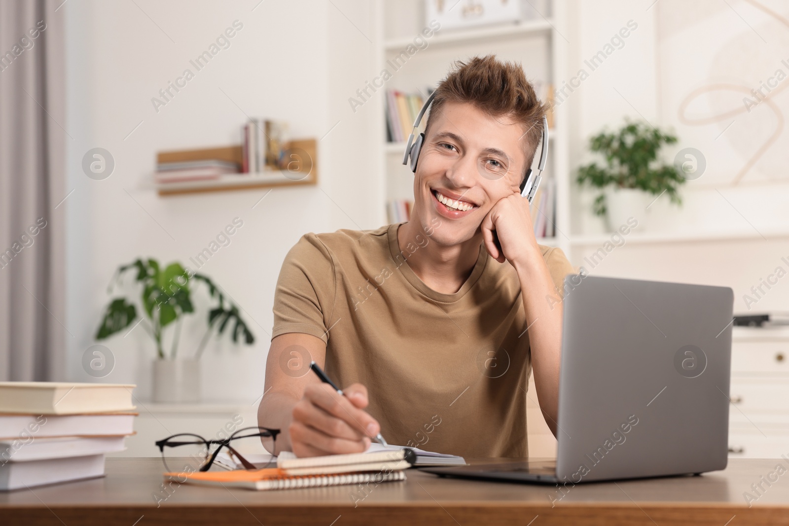 Photo of Student in headphones studying at table indoors