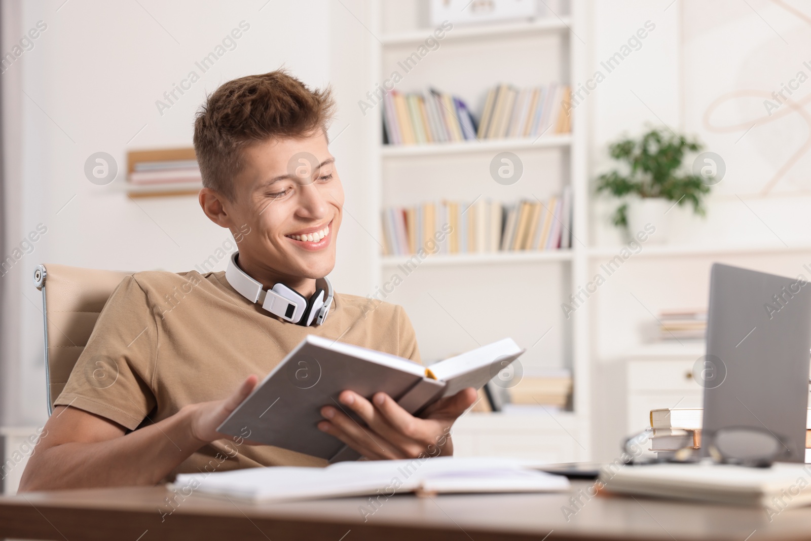 Photo of Student with book studying at table indoors