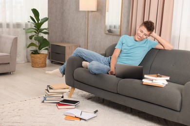 Student studying with laptop on sofa at home