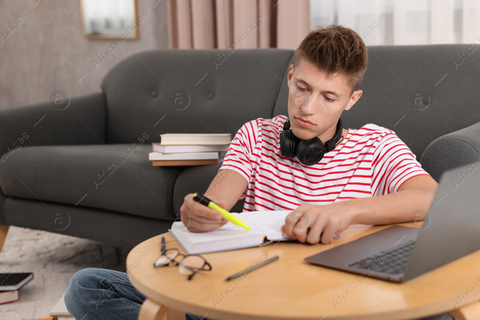 Photo of Student with headphones studying at table indoors