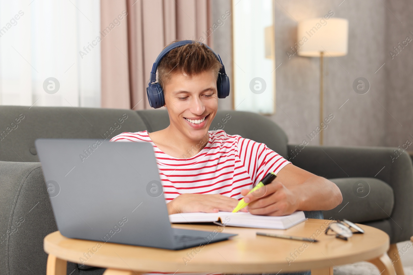 Photo of Student in headphones studying at table indoors