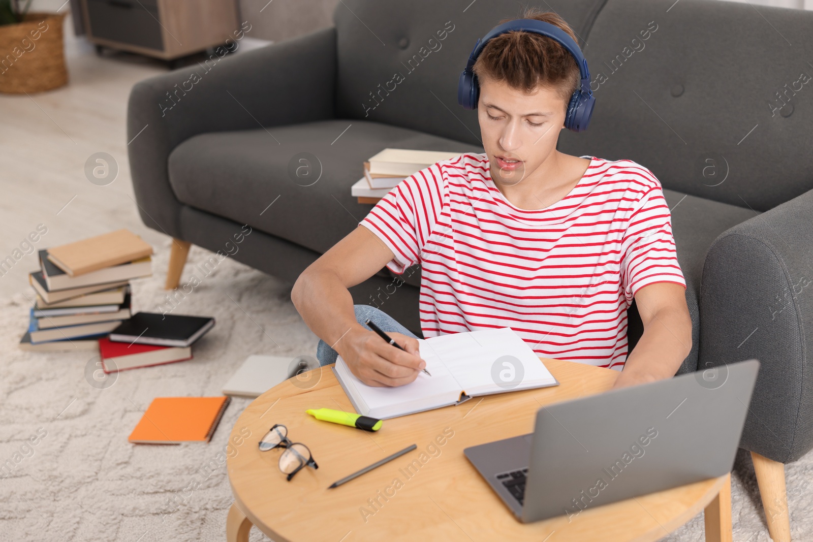 Photo of Student in headphones studying at table indoors