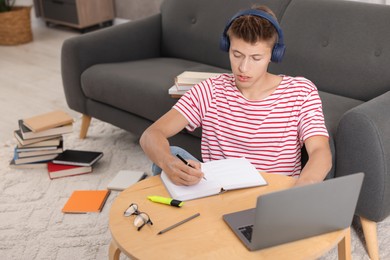 Photo of Student in headphones studying at table indoors