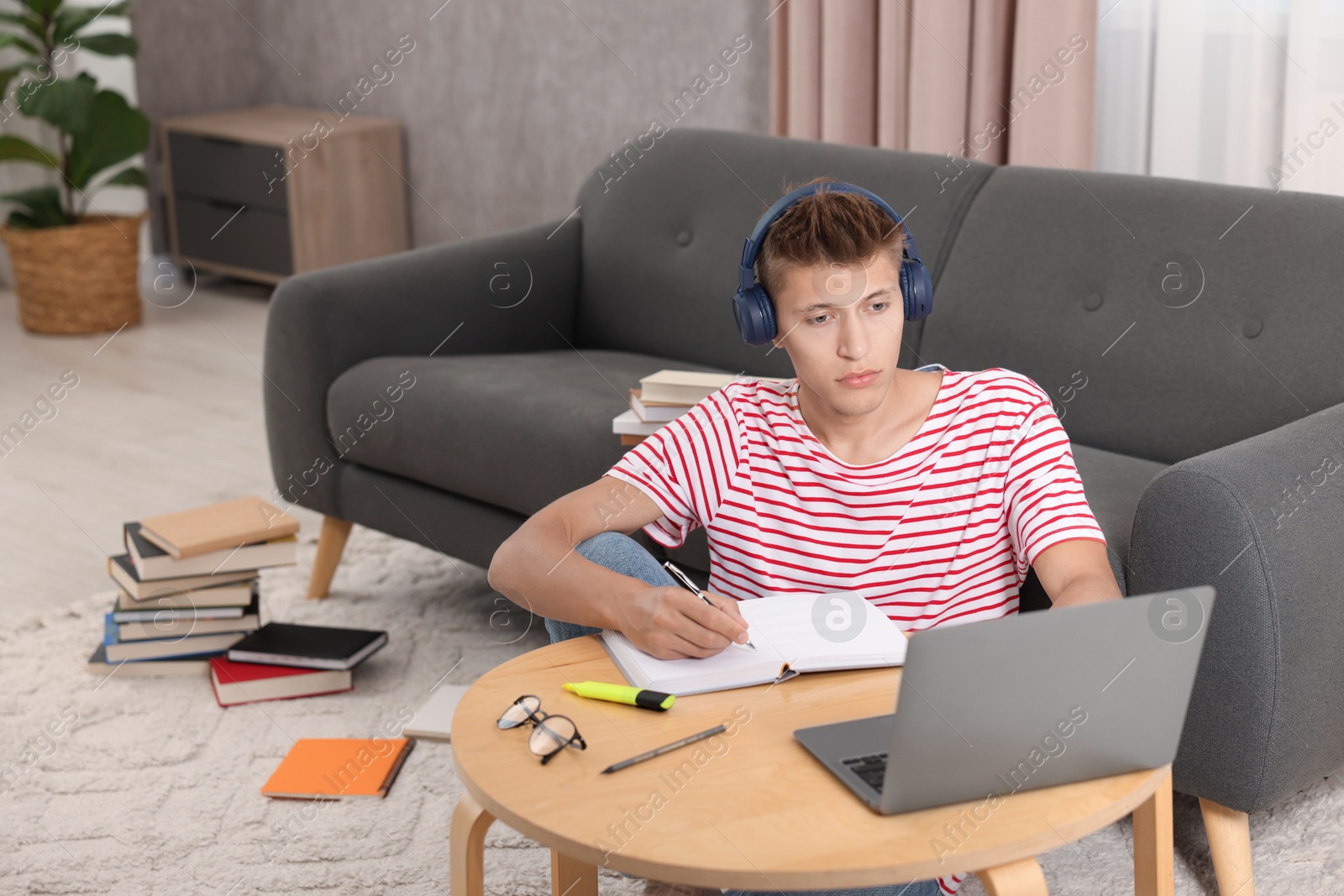 Photo of Student in headphones studying at table indoors