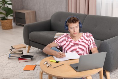 Student in headphones studying at table indoors