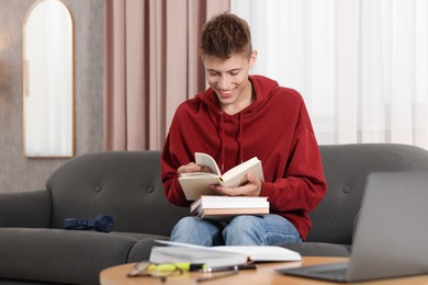 Photo of Student with books studying on sofa at home