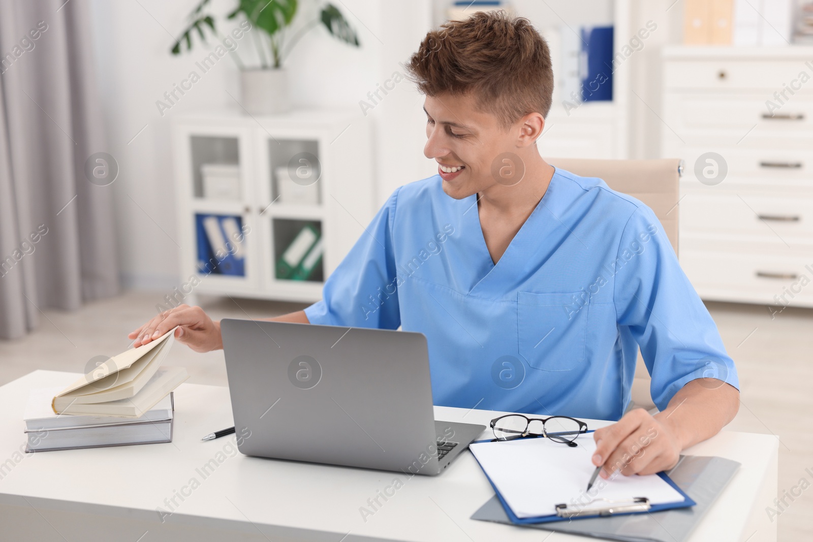 Photo of Medical student in uniform studying at table indoors