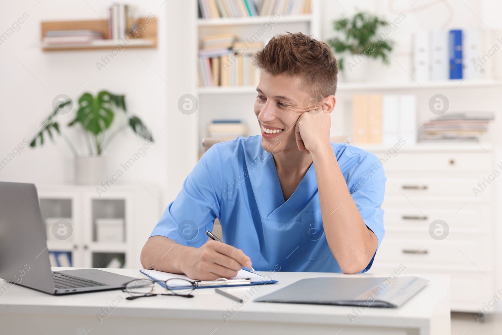 Photo of Medical student taking notes while studying at table indoors